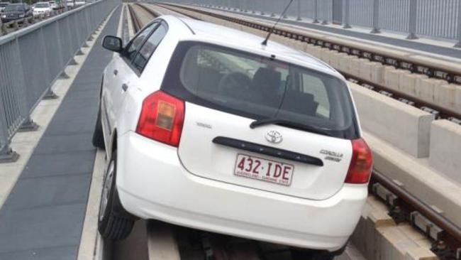 A white Toyota corolla hatch us seen stuck on the same light rail bridge as where an unmarked police car was stranded just hours earlier...