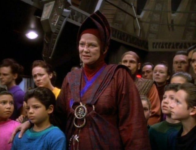 Kai Winn smiling condescendingly surrounded by Bajoran children on Deep Space Nine