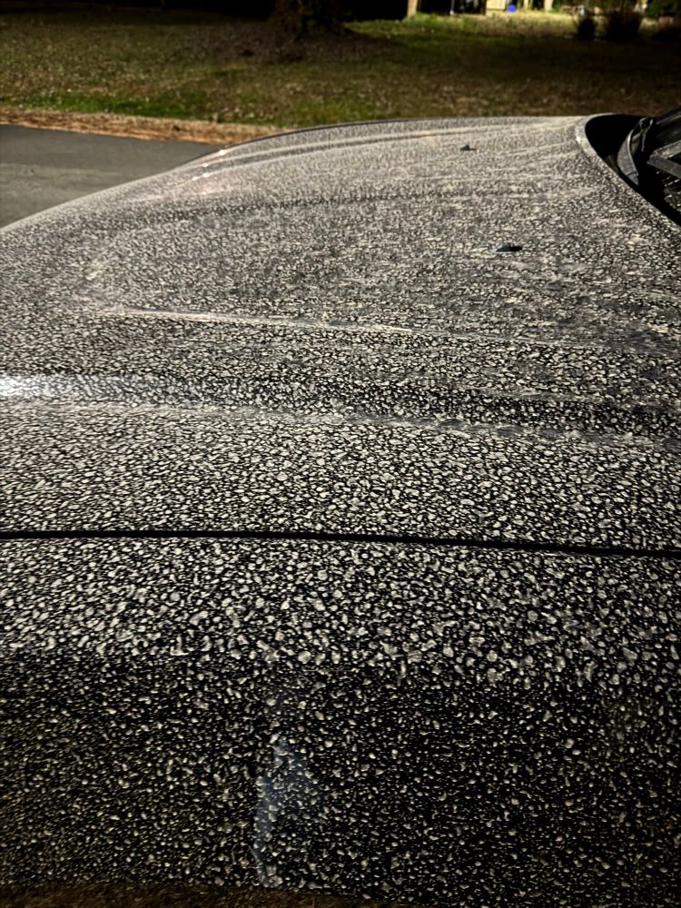 Hood of a black dodge charger covered in splatters of rain drops and soot
