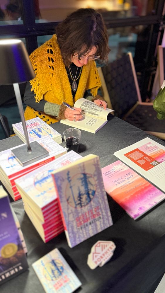 Me signing books! The focus is on me, with the stack of books in the foreground slightly blurred 