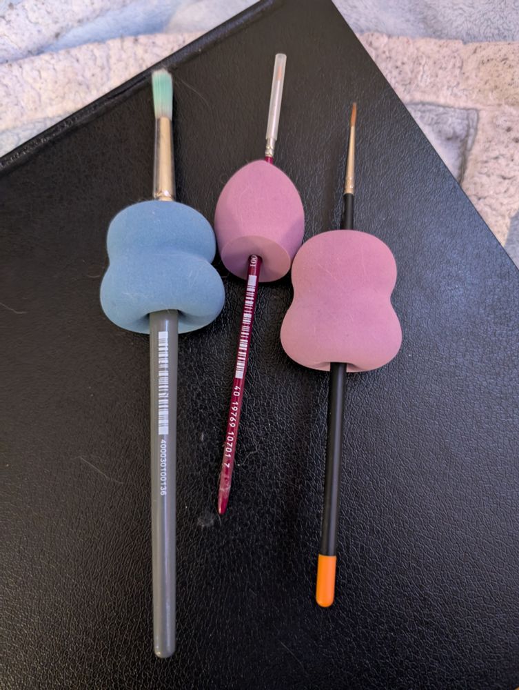 Three sizes of paintbrush with round makeup sponges. The paint brushes are speared through the center of the sponges to provide a larger grip area.
