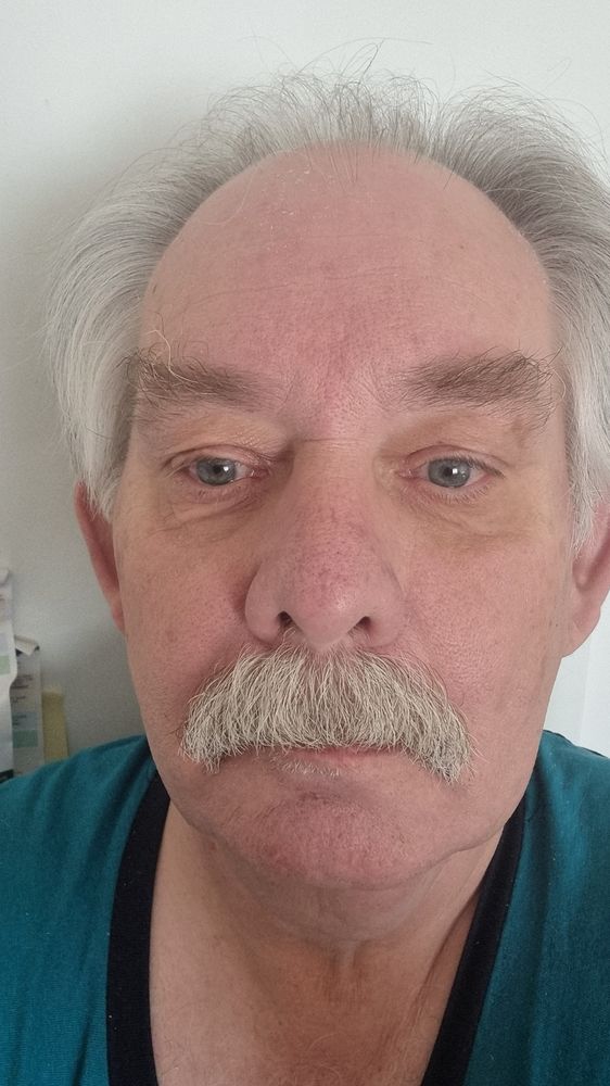 Ein ältere weisshariger Herr schaut in die Kamera. 
