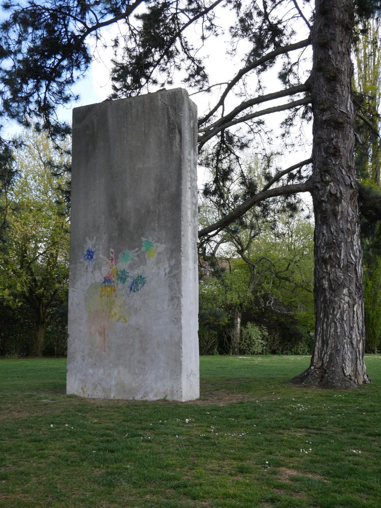 Monolithe de béton debout dans un parc au milieu des arbres.