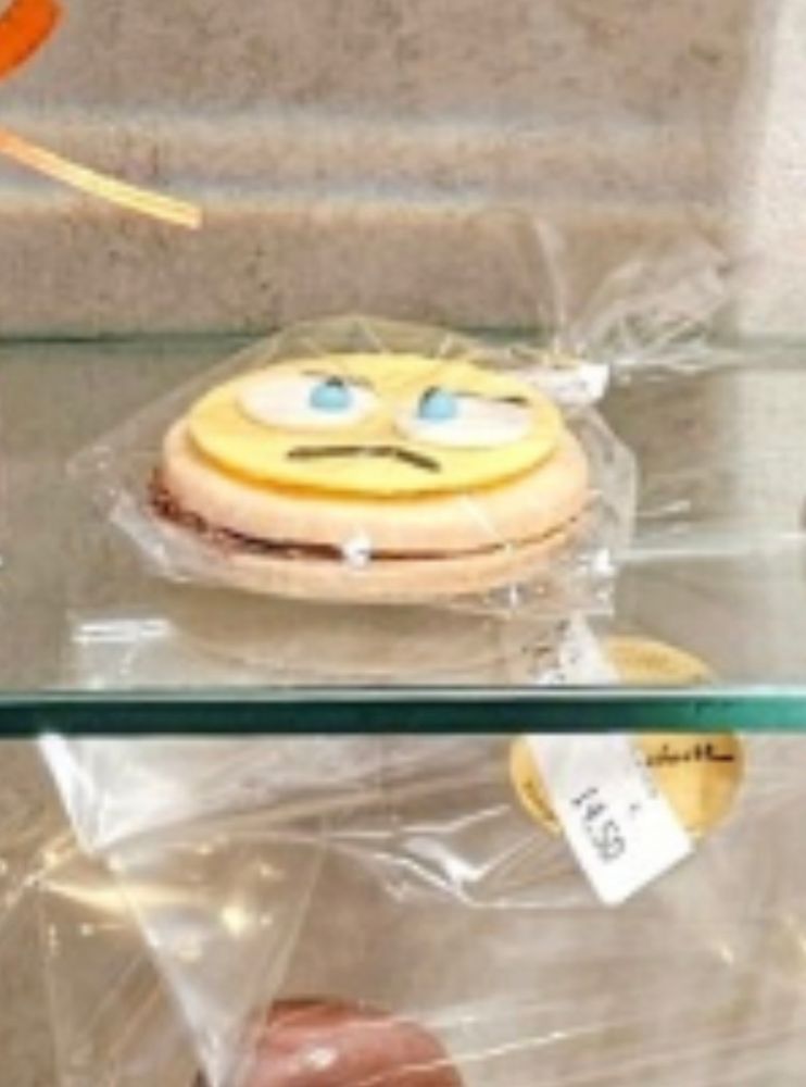 In Folie eingepacktes Gebäck in Form eines grimmig drein blickendem Emoji 