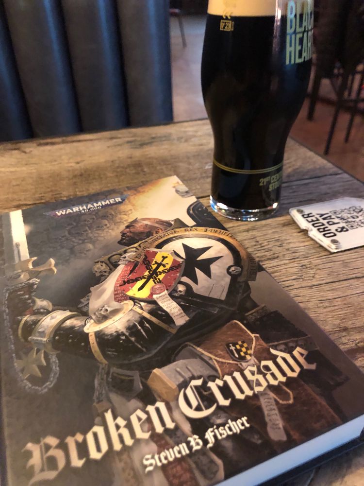 Picture a table in a pub, with a pint of stout on the right and a hardback copy of Broken Crusade by Steven B Fischer in the middle. 