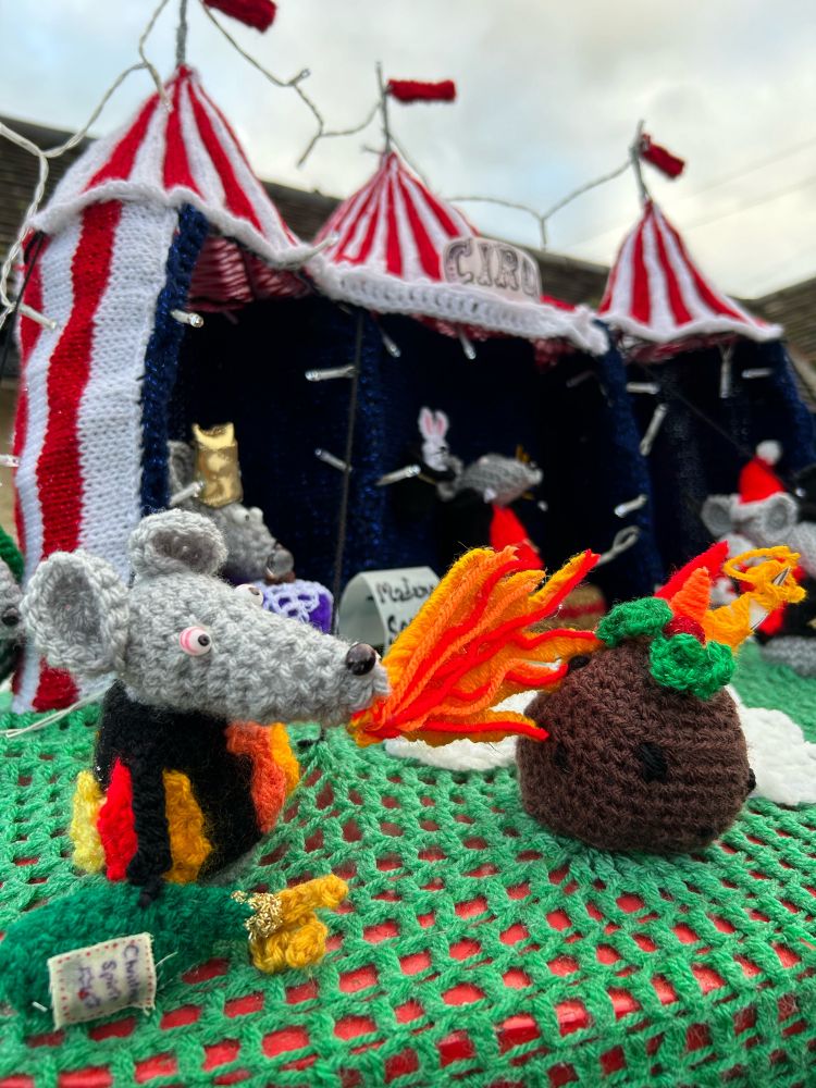 火吹き芸のネズミがブランデーたっぷりのクリスマスプディングに火をつけている