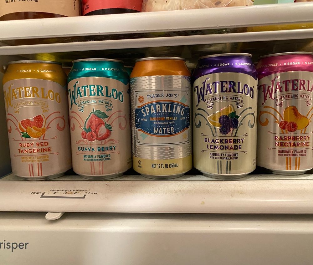 A selection of 5 sparkling water flavors in a refrigerator; Ruby red tangerine, guava berry, tangerine vanilla, blackberry lemonade, raspberry nectarine