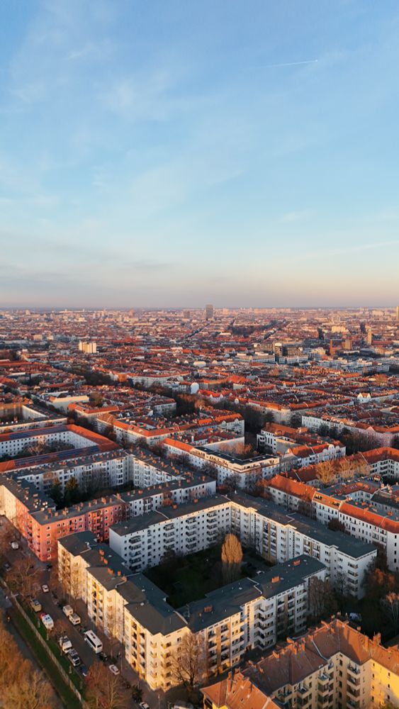 a picture looking down on a sea of apartment buildings blocks littering the city skyline to the horizon, in Impossible Germany. 