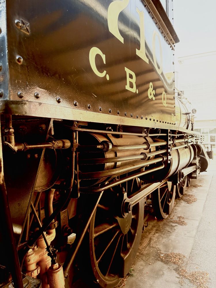 Black and white, side view photo of an antique locomotive with the letters C.B. & Q. stenciled on the side.  