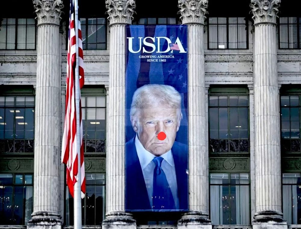 Chairman Mao style giant picture of Trump on an unofficial building but with a clown nose.