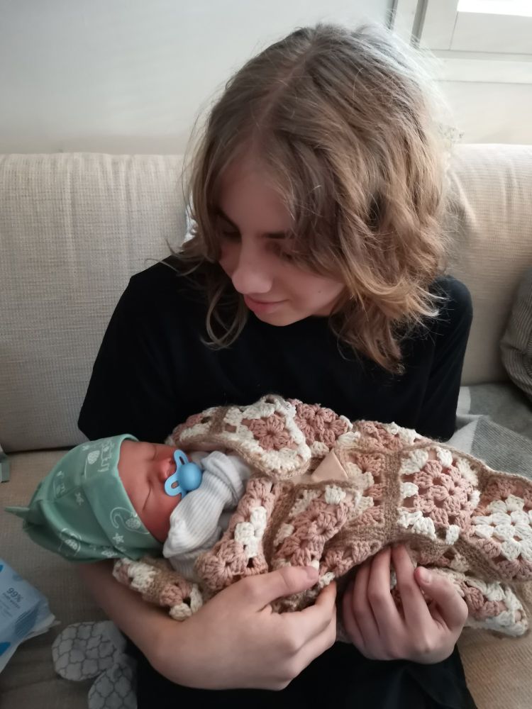 Esikoinen pitää vastasyntynyttä kuopusta sylissään sohvalla.