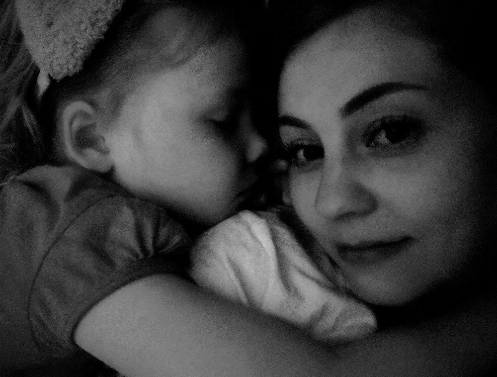 Mustavalkoinen kuva minusta ja kolmannesta lapsesta, hän nukkuu kainalossani viiden vuotiaana.