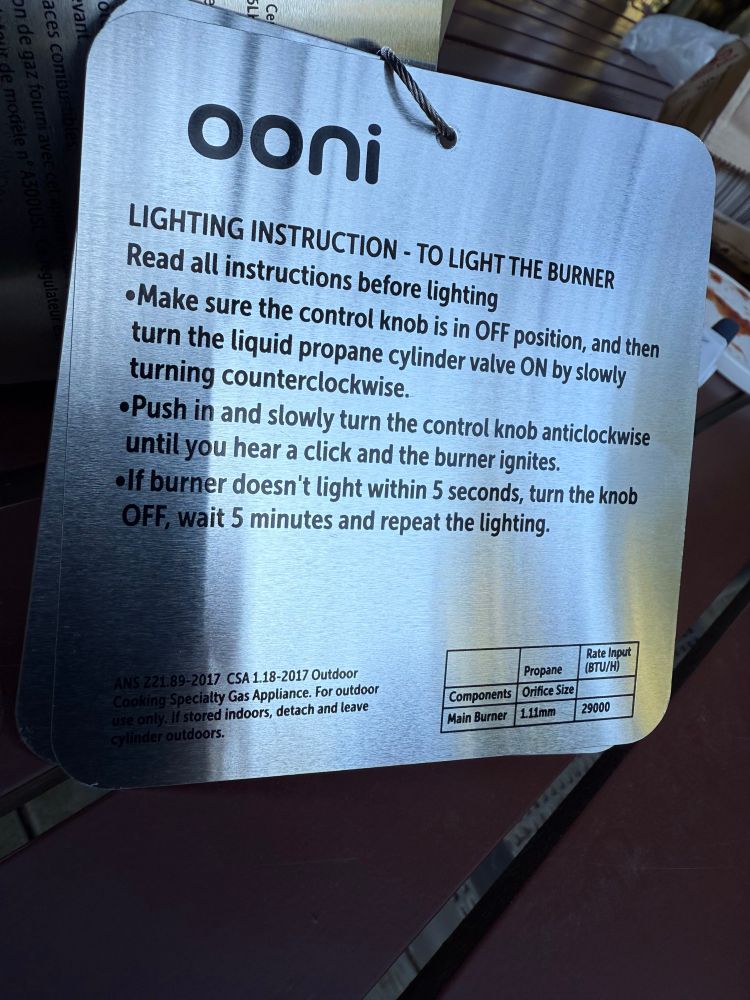Ooni home pizza oven “Lighting Instructions,” printed on a metal sheet and attached to an oven leg. They read: LIGHTING INSTRUCTION - TO LIGHT THE BURNER
Read all instructions before lighting
• Make sure the control knob is in OFF position, and then turn the liquid propane cylinder valve ON by slowly turning counterclockwise.
• Push in and slowly turn the control knob anticlockwise until you hear a click and the burner ignites.
• If burner doesn't light within 5 seconds, turn the knob OFF, wait 5 minutes and repeat the lighting.