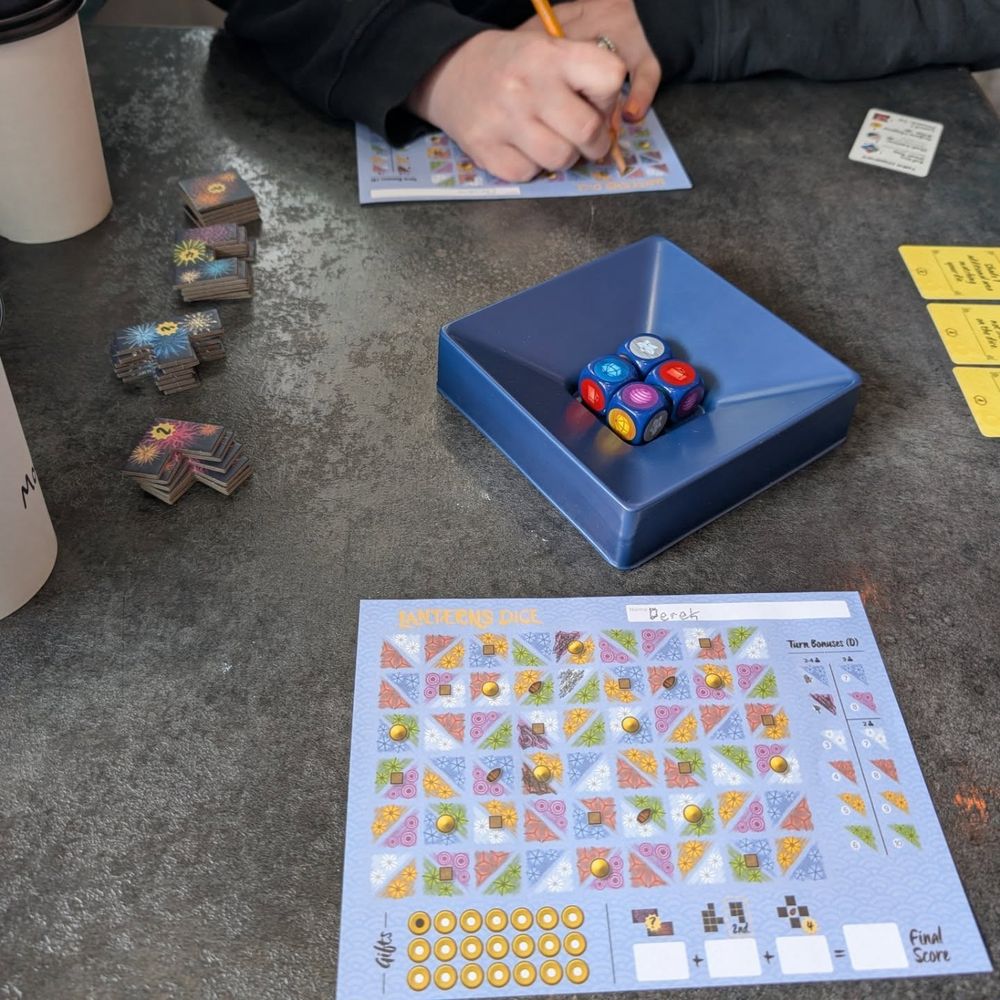 A game of Laterns Dice roll and write game with coffee on the side.