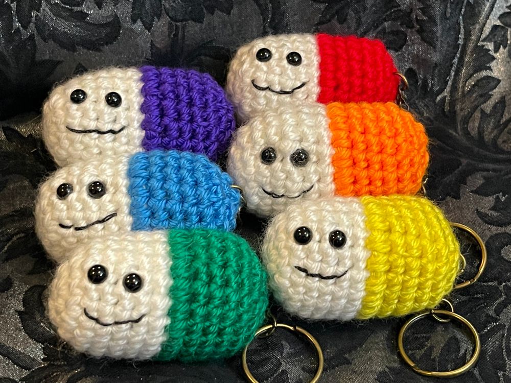 Crochet pills, in rainbow colors, with tiny smiling faces stitched on