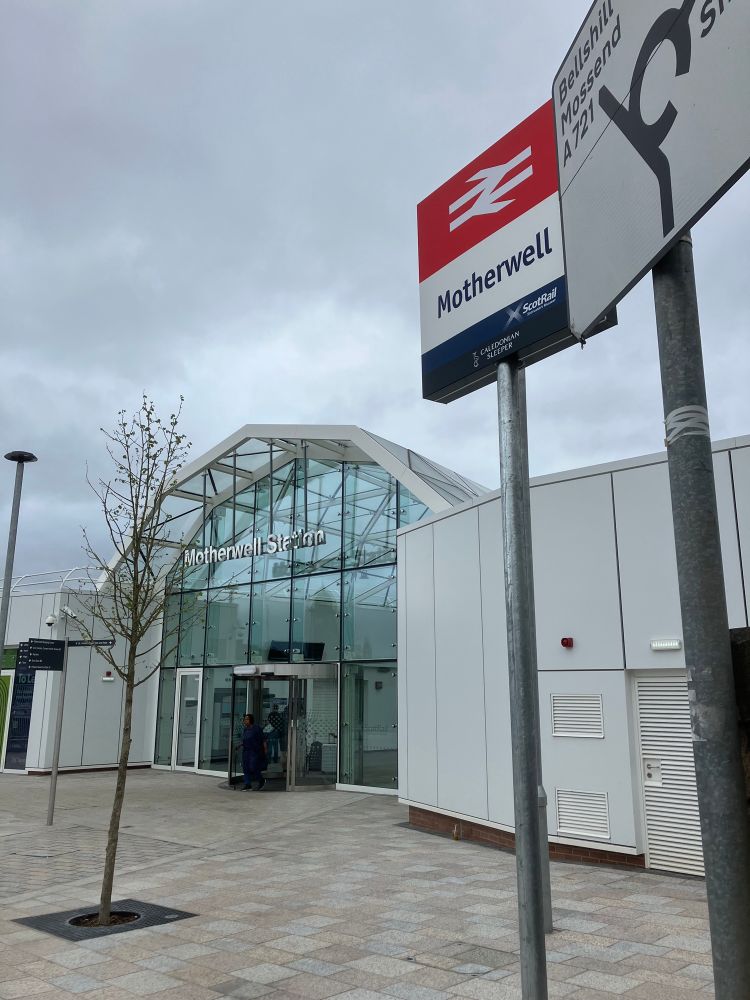 Sign outside Motherwell train station with British Rail logo at top in white on red background and Scotrail logo at foot in white on dark blue band 