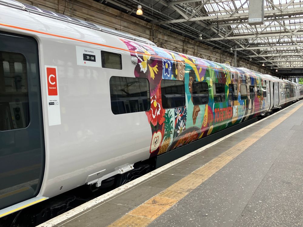 Avanti West Coast train carriage C with colourful illustration of different people and plants and text: “Together we roll”