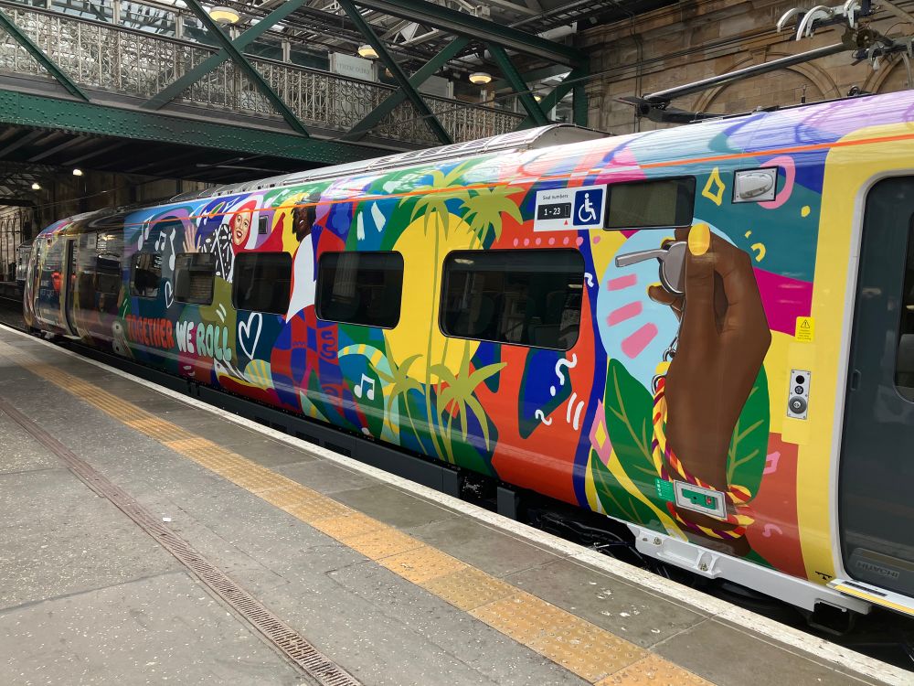 Avanti West Coast train with colourful illustration of different people and plants and text: “Together we roll”