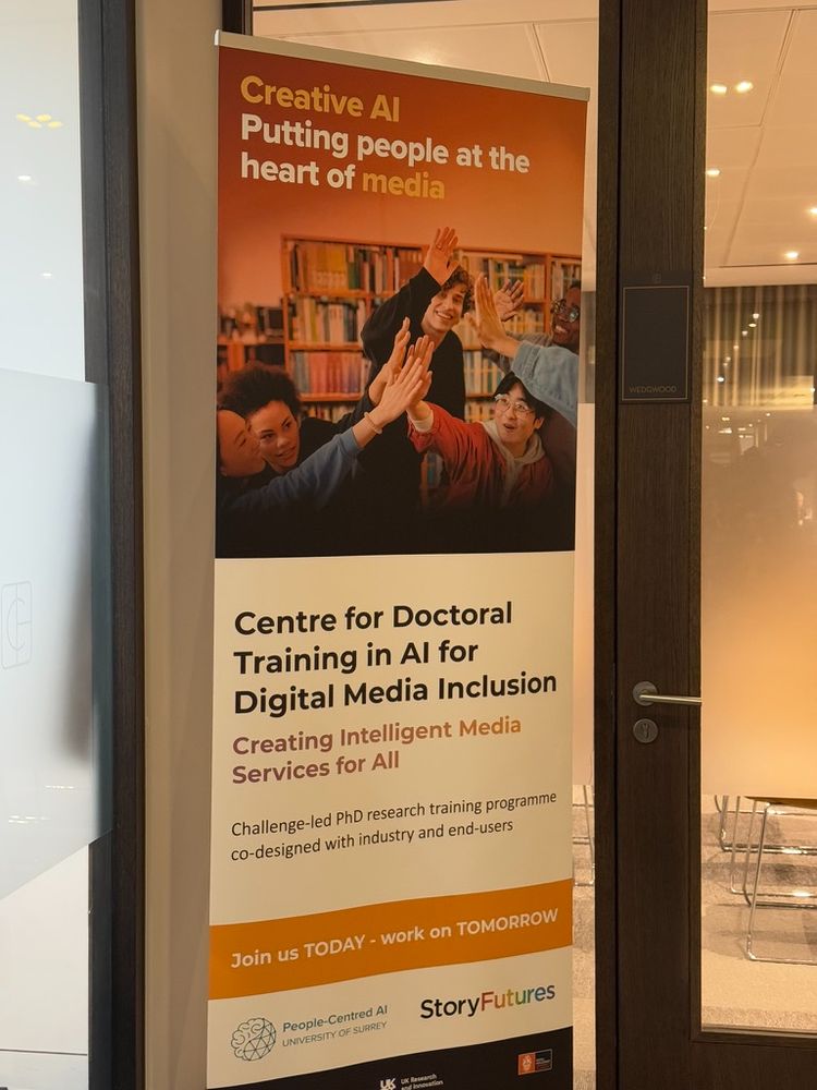 A floor-standing banner promoting the Centre for Doctoral Training in AI for Digital Media Inclusion. The headline reads “Creative AI: Putting people at the heart of media,” emphasising a human-centric approach. The banner describes the Centre as a challenge-led PhD research training programme co-designed with industry and end-users, focusing on creating intelligent media services for all to ensure digital media inclusion. A call to action urges viewers to “Join us TODAY - work on TOMORROW,”