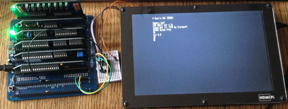 Photo of a rc2014 and a HDMIPi display with a small solderless breadboard inbetween with a single chip on it, connected to both via jumper wires.  The RC2014 is on and the display shows the boot information showing that BASIC is running.