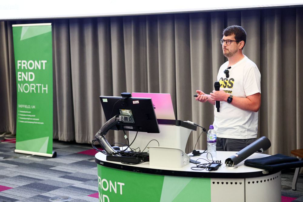 Andy Bell at the lectern wearing a CSS Programmer t-shirt 