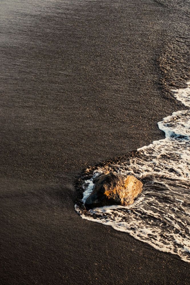 Plage de sable noir éclairée par un coucher de soleil