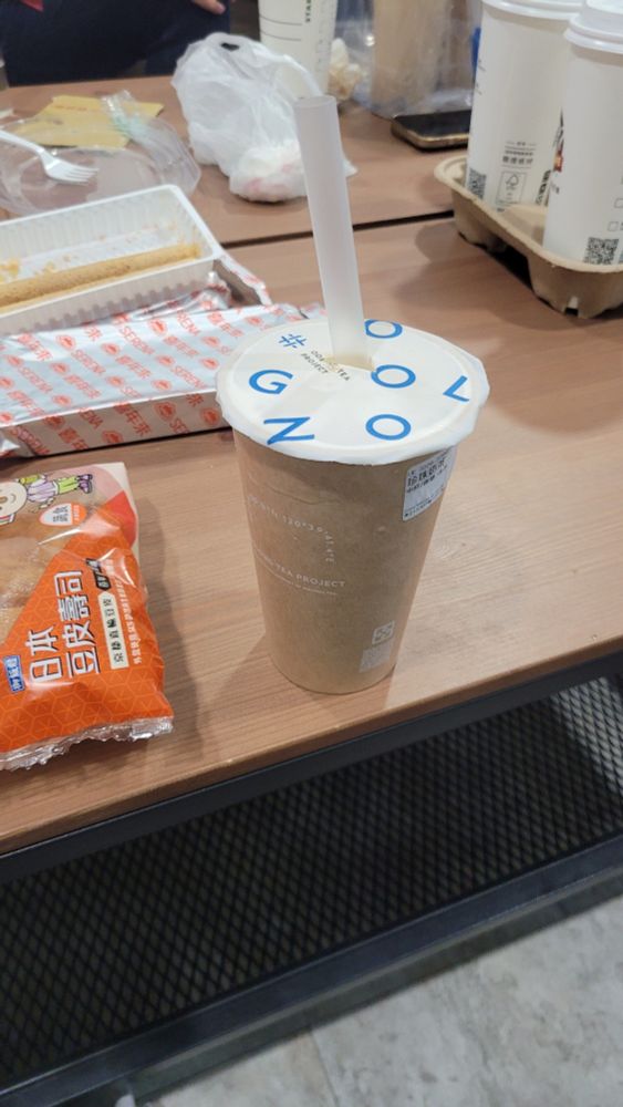 Photo of a boba on a coffee table, surrounded by other snacks and food.