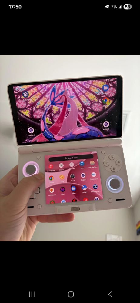 Foto de uma mão segurando o videogame Ayn Thor. Um dispositivo com duas telas, uma em cima e outros em baixo.