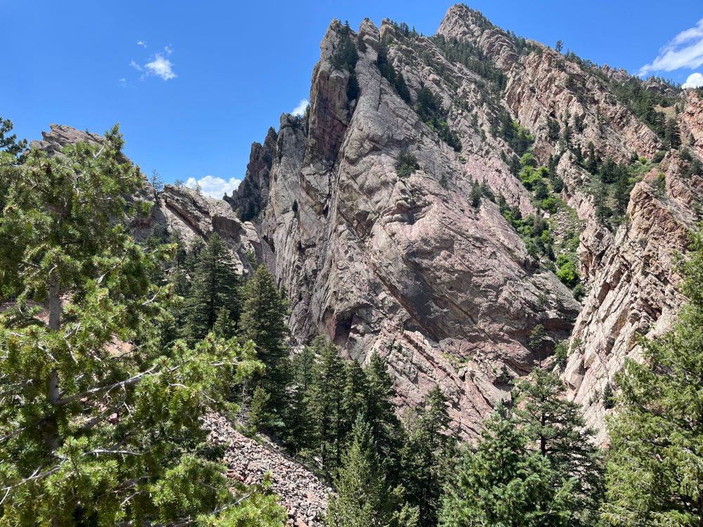 rocky tree covered colorado mountain peak and mostly clear sky