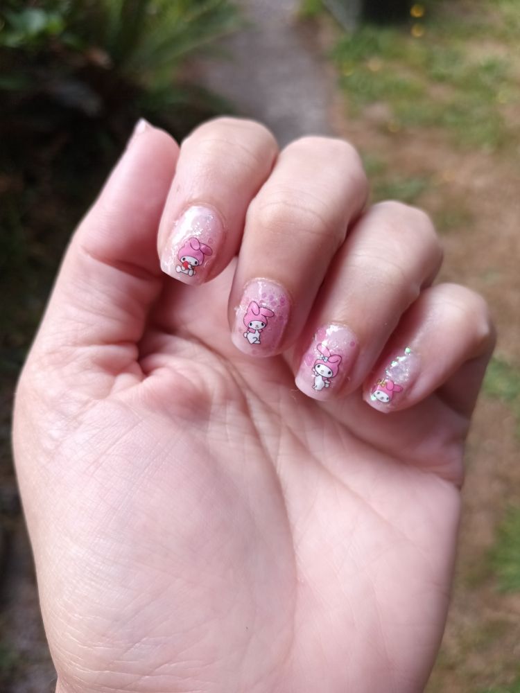 A pale pink glitter manicure with sanrio my melody decals.