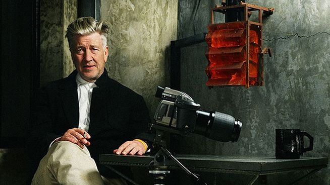 Photographie de David Lynch,  à côté d’une caméra et d’une tasse 