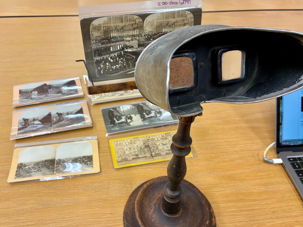 Image of a 19th c stereoscope on a stand, with a selection of 19th and early 20th c stereographs mounted on card