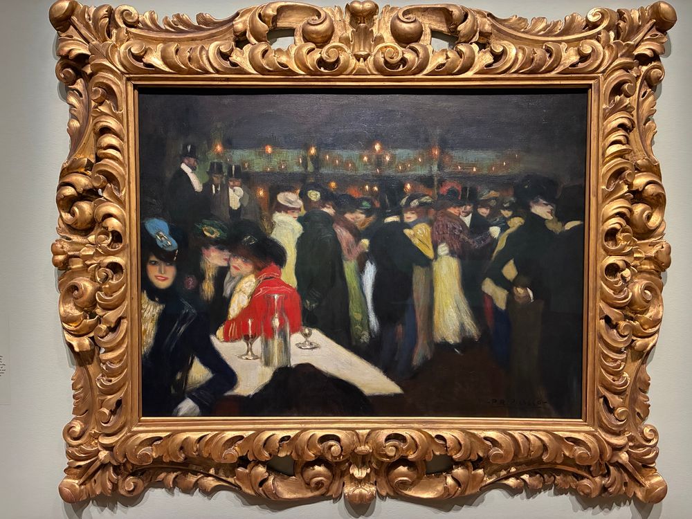 Painting by Picasso of Parisian street life. An early canvas by him, it is figurative and features crowds of dancers wearing evening dress, mostly dark in colour with a few pops of yellow and red. The painting is framed in a large, ornate gilt frame which rather overwhelms it. 