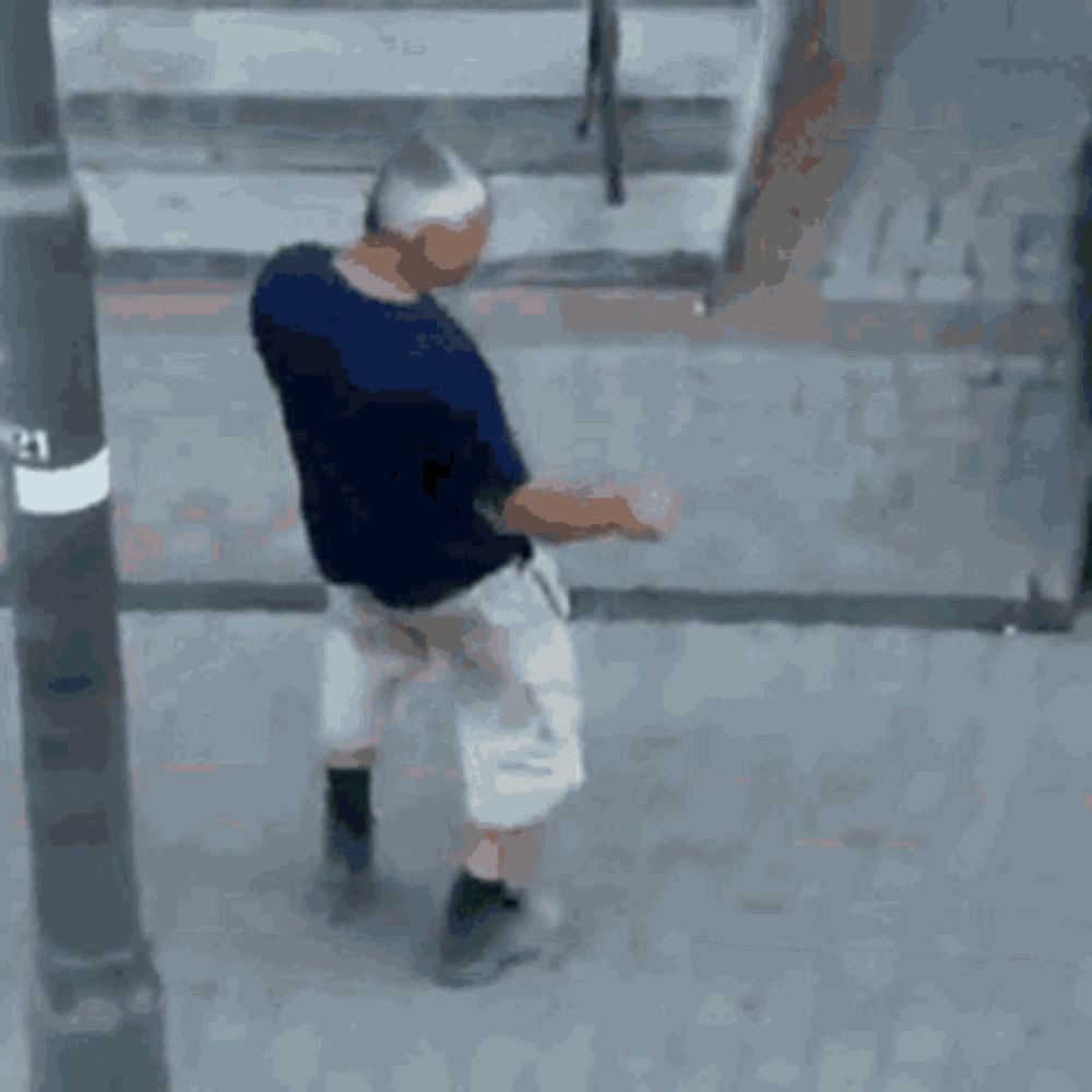 a man in a blue shirt and white shorts is walking down a street .