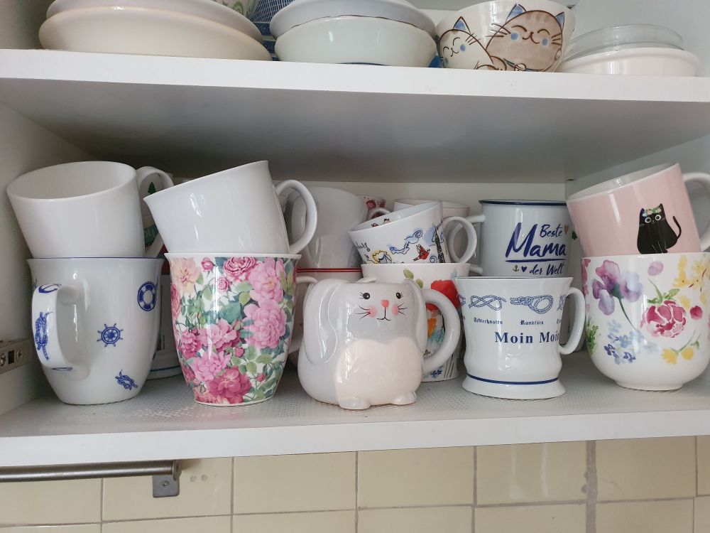 Das Innere von einem Schrank ist zusehen mit unterschiedlichen Tassen zum Teil.