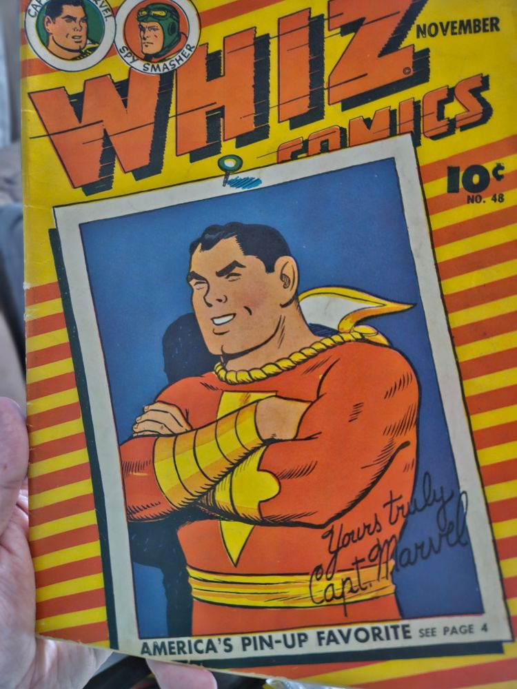 The cover to Whiz Comics, No. 48. The cover has a yellow and orange striped background and features an autographed pin-up of America's Favorite Superhero, Captain Marvel. There are pictures of Marvel and Spysmasher in the upper left corner.