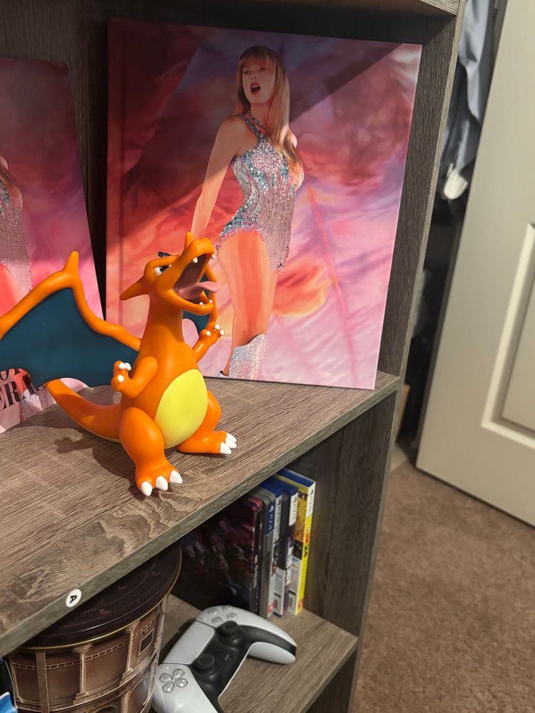 Charizard figurine I got from Japan set up in front of the Eras Tour book