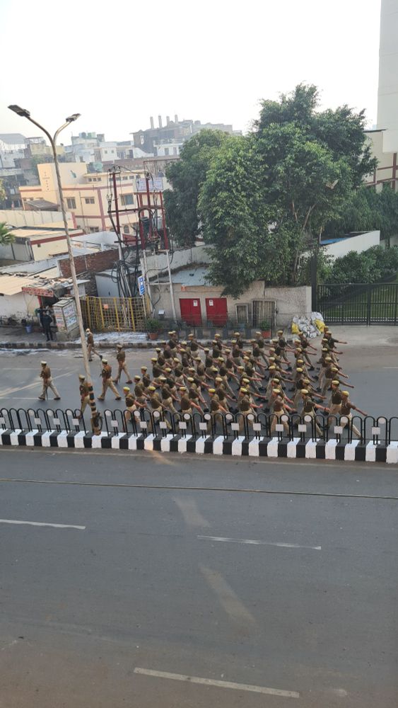 People in uniform walking in neat rows down a wide street.