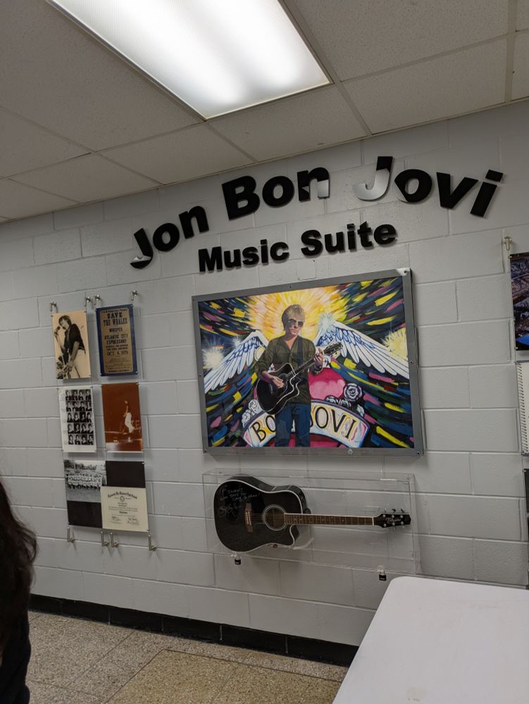 A wall at my old high school with posters and a signed guitar, identifying the Jon Bon Jovi Music Suite.