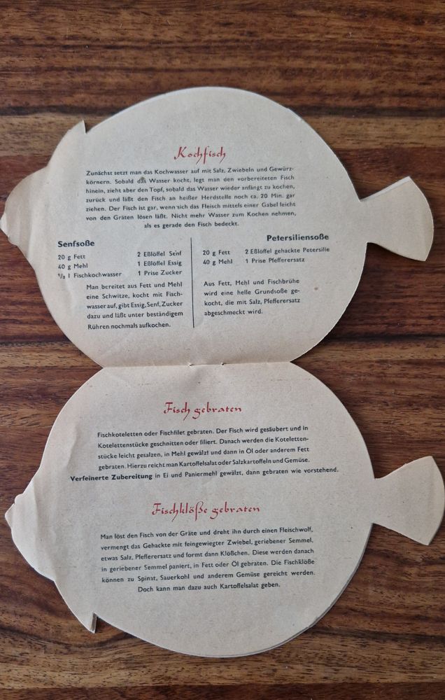 Two open pages of the fish-shaped booklet. The text praises the achievements of East German fisheries and promotes fish as a healthy food. The layout is in a stylized oval format matching the fish shape.