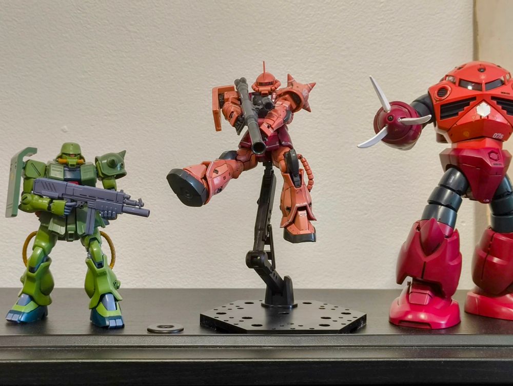 Une maquette gunpla du zaku 2 de Char en pose de combat sur une action base