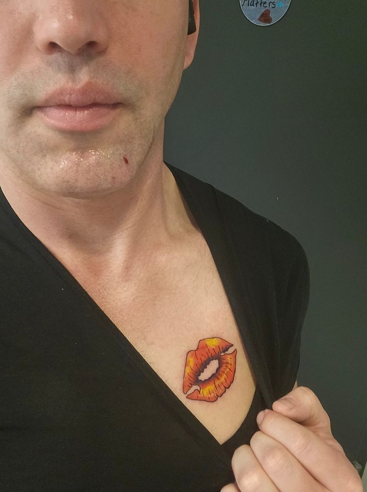 A close-up of a human with their hand on the collar of their wool t-shirt.

They're pulling the collar of their shirt down and to their left to expose a pectoral tattoo reminiscent of the iconography of the character "Scarlet Woman" from a popular social deduction game: Blood on the Clocktower.