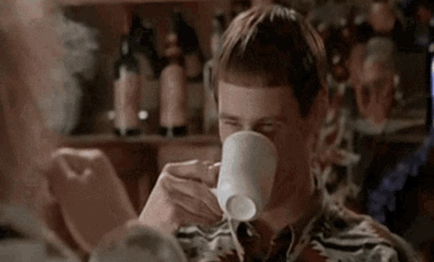 Jim Carey in Dumb & Dumber smiling while drinking from a white mug