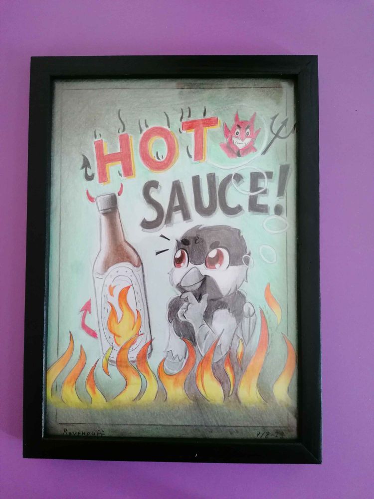 The hand drawn art of Burd in a hot sauce ad, framed and lying on a purple table surface. 
