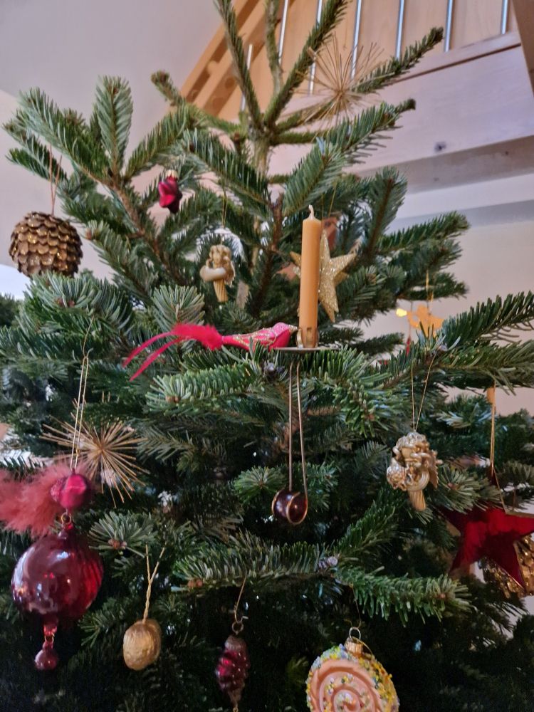 Weihnachtsbaum der jetzt mehr geschmückt ist mit Kugeln, Glasvögeln, goldenen Sternen, Kerzen und goldenen Engeln aus Nudeln