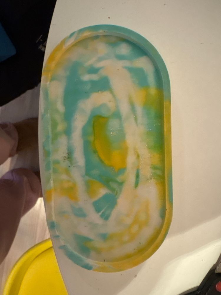 Ein ovales Tablett in weiß grün gelbem farb. durcheinander 