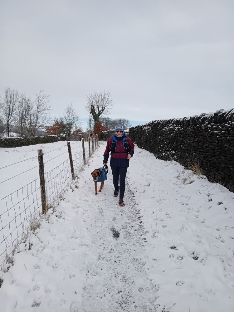 Chrissie and Pebbles running on a snowy track.