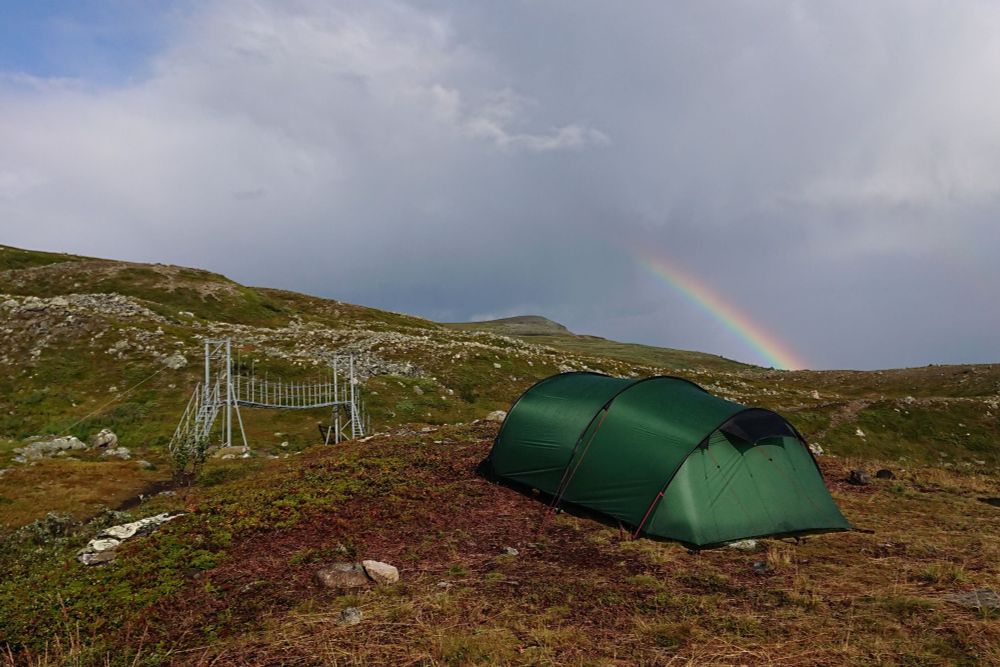 A footbridge, our tent and a rainbow on a mountainside in Arctic Sweden. 