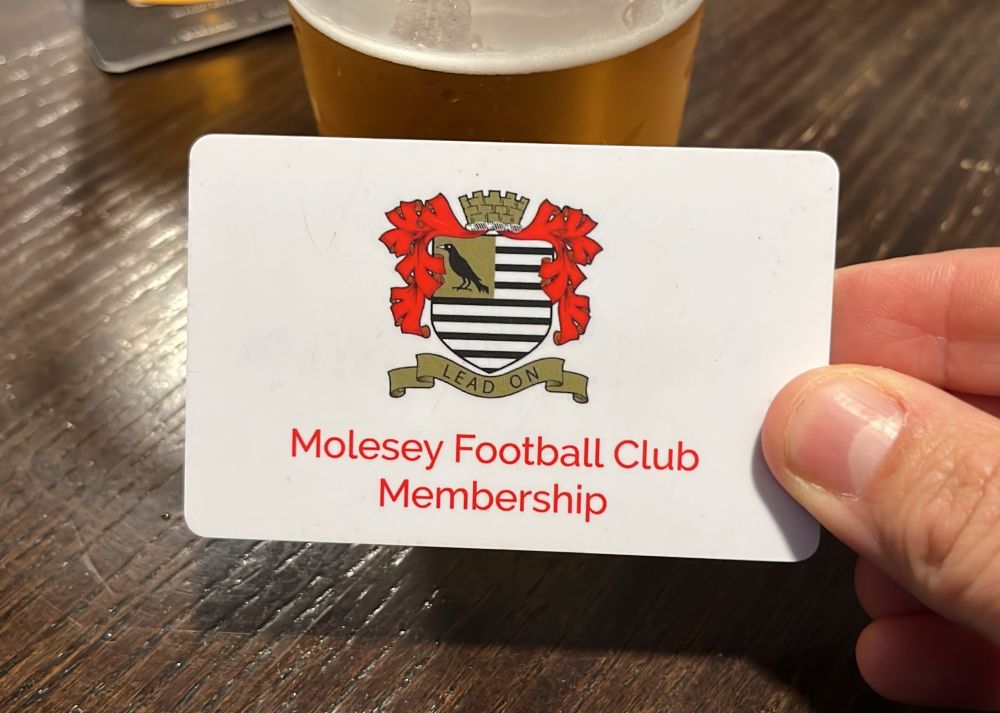 A close up of me holding a membership card for Molesey Football Club. There is a pint of beer in the background.
