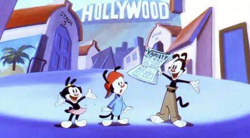 The characters Dot, Wakko and Yakko Warner from the animated series "Animaniacs", standing in a studio lot with the Hollywood sign behind them and with Yakko holding an issue of Variety Magazine.